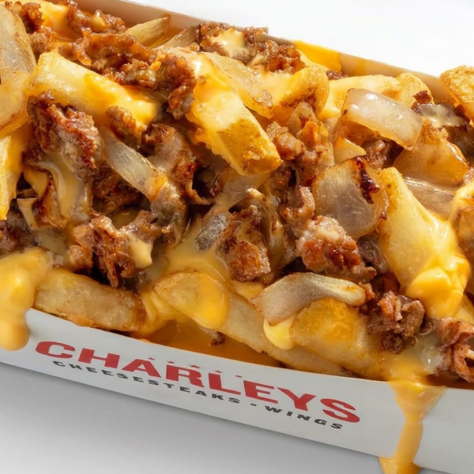 Loaded fries topped with crispy beef, grilled onions, and melted cheese sauce in a Charleys Cheesesteaks box.
