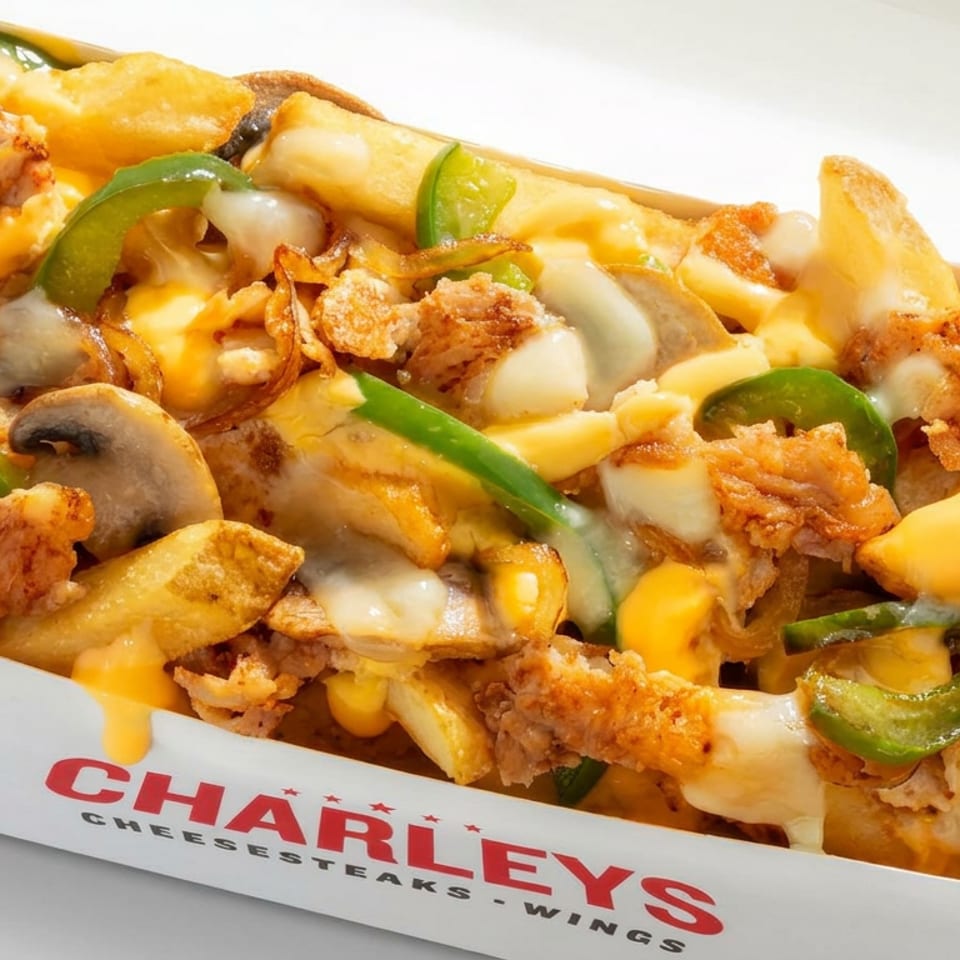Loaded cheese fries topped with fried chicken, mushrooms, green peppers, onions, and melted cheese in a Charley’s takeout box.
