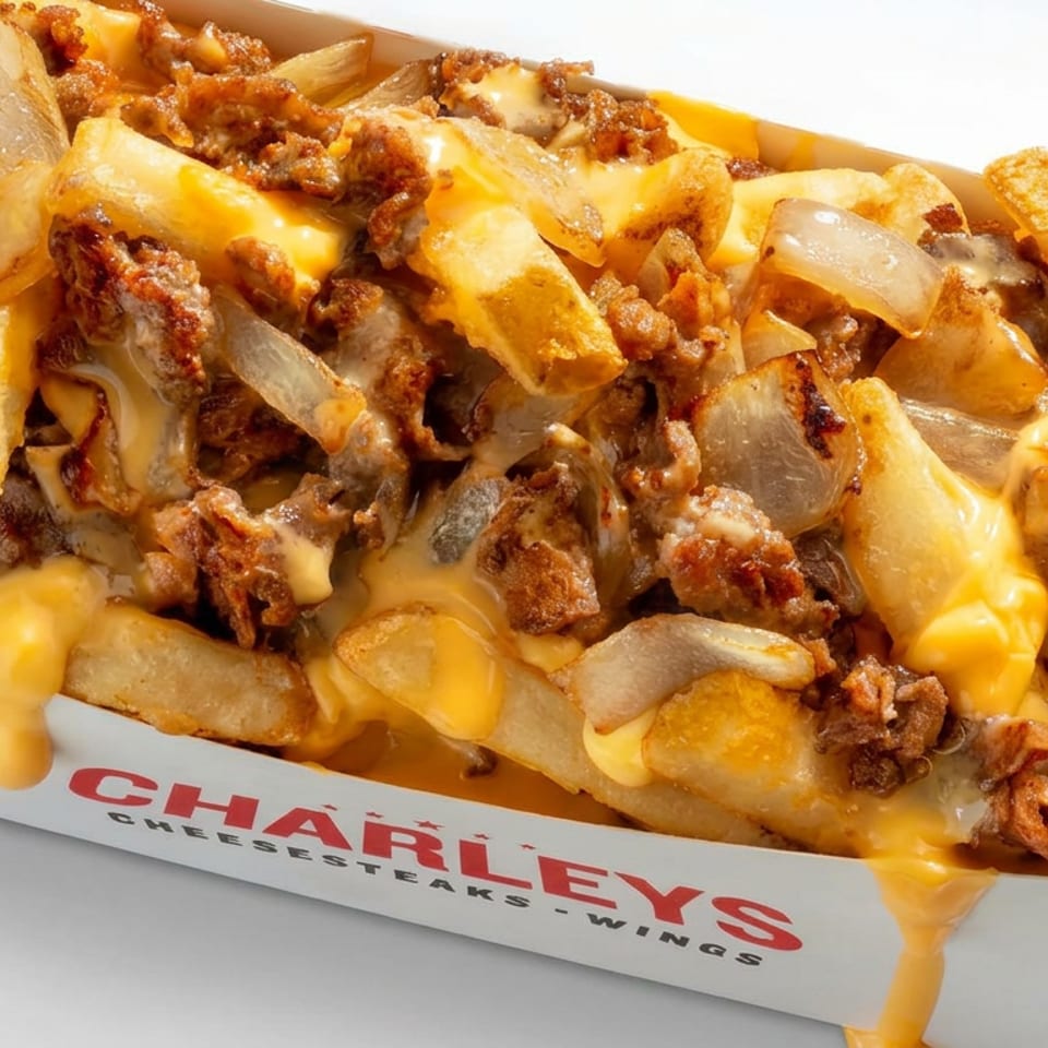 Cheesesteak fries topped with melted cheese, chopped steak, and onions in a Charleys Cheesesteaks box.