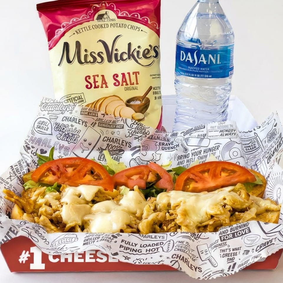 Cheese-covered loaded fries with tomato slices in a branded basket, accompanied by Miss Vickie's chips and a Dasani water bottle.